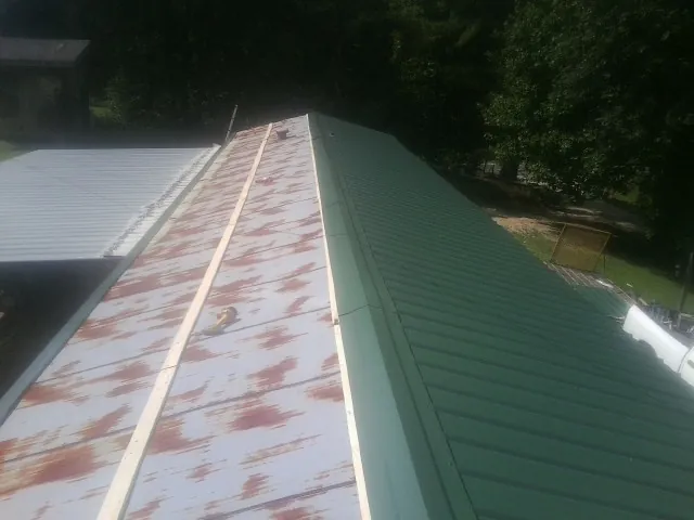 Old rusted panels beside newly installed green metal roofing — Wind Damage Roof Repair by Roofing Brothers in Woodhull