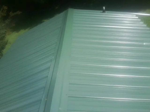 New green metal panels meeting at the ridge of a roof — Flat Roof Repair work by our crew in Woodhull