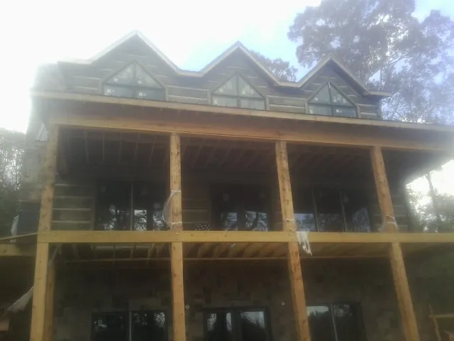 Dormers and porch framing on a large log home under construction — Roof Coating work by our crew in Woodhull