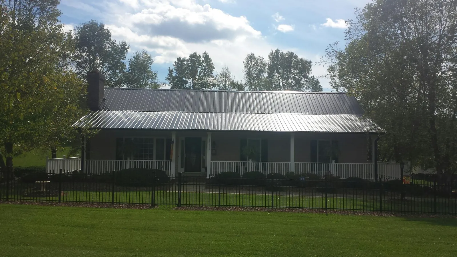 Gray metal roof on a brick ranch with a full width front porch — Gutter Guard Installation work by our crew in Woodhull