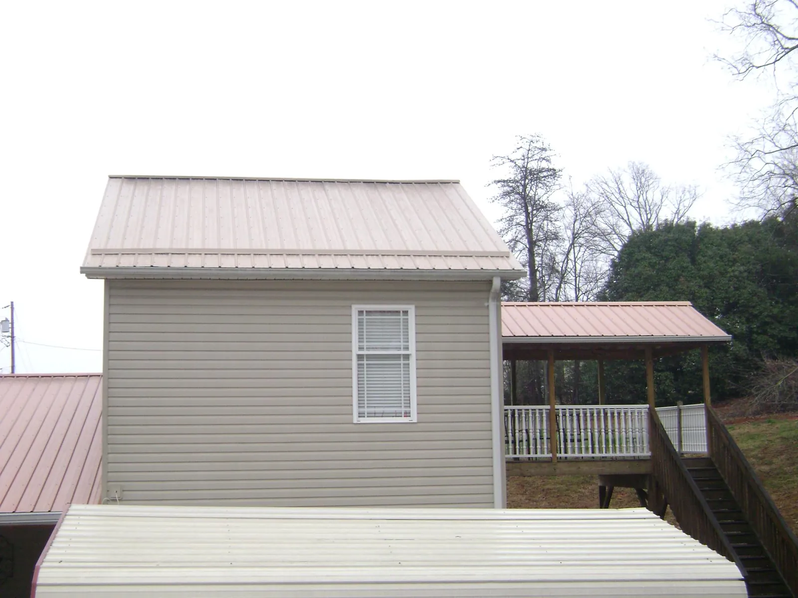 Tan metal roofs on a two story addition and attached porch, from a Roof Replacement job in Woodhull