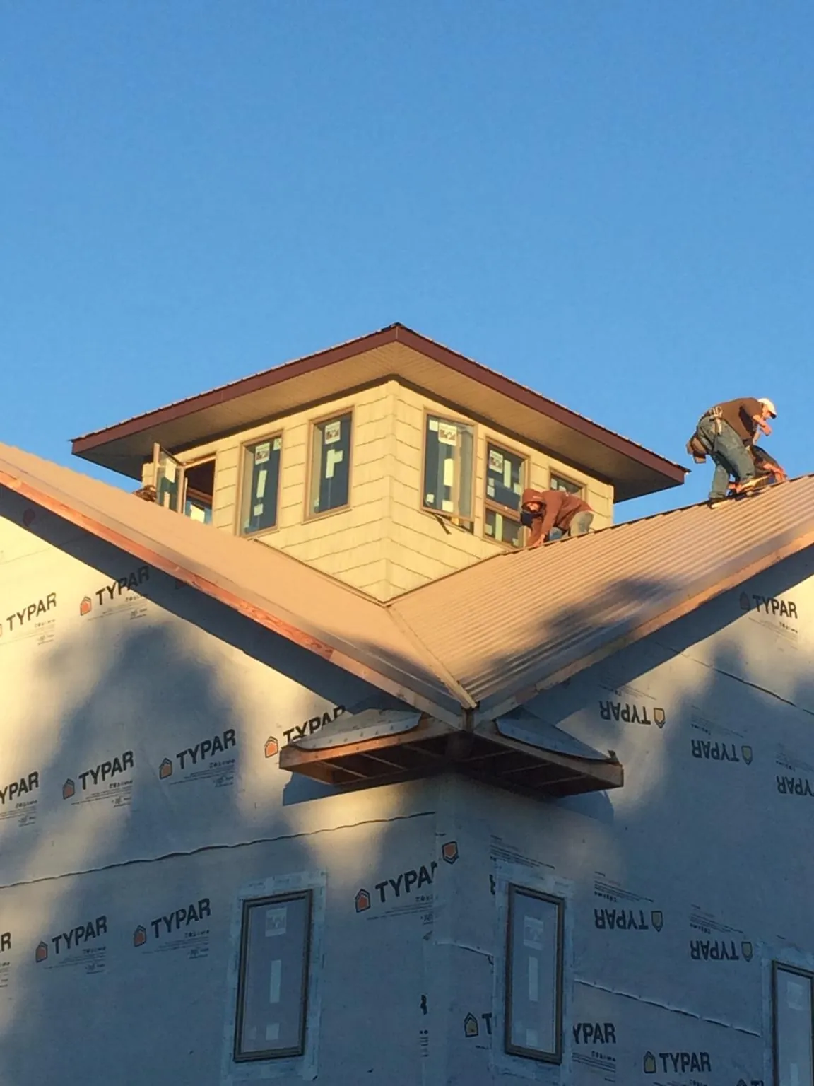 Roofers working around a rooftop cupola on a new metal roof at sunset — Roof Waterproofing in Woodhull by Roofing Brothers
